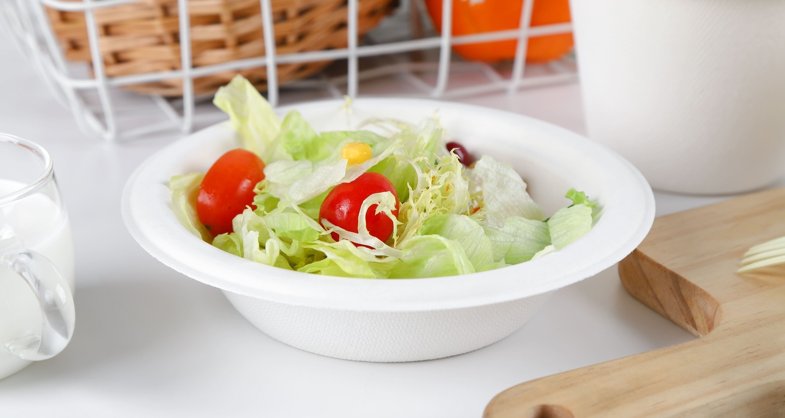 An oily pasta dish next to a bagasse bowl with a cautionary red X over it